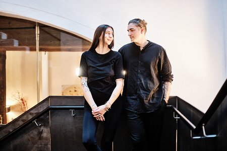 Laura und Maximilian Schmidt in schwarz gekleidet schauen einander lächelnd an.