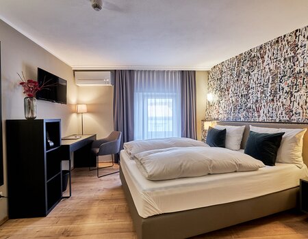 Modernes Hotelzimmer mit Doppelbett, Schreibtisch und stilvoller Wandgestaltung.